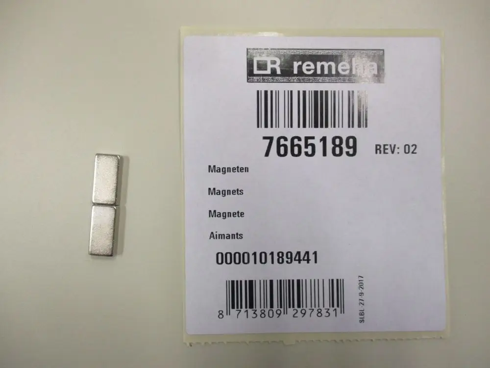 Zwei rechteckige Magnete der Marke Remeha neben einem Etikett mit Artikelnummer und Informationen in mehreren Sprachen.